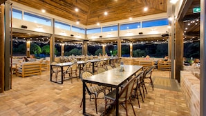 An outdoor dining area with multiple tables and chairs, large windows, and a wooden ceiling. - Harrigan's Hunter Valley (Pokolbin)