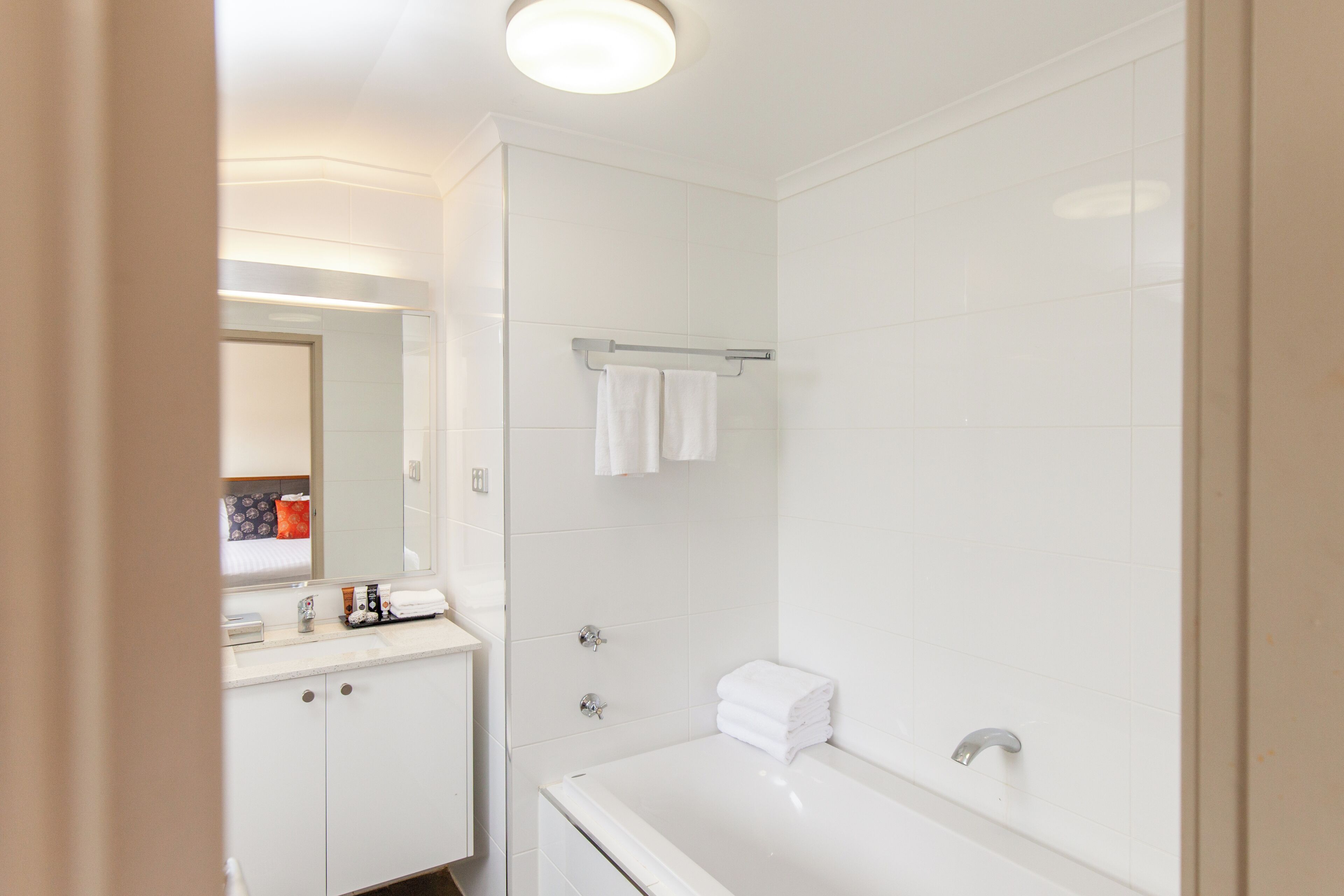 A modern bathroom with a white sink, mirror, and shower area.