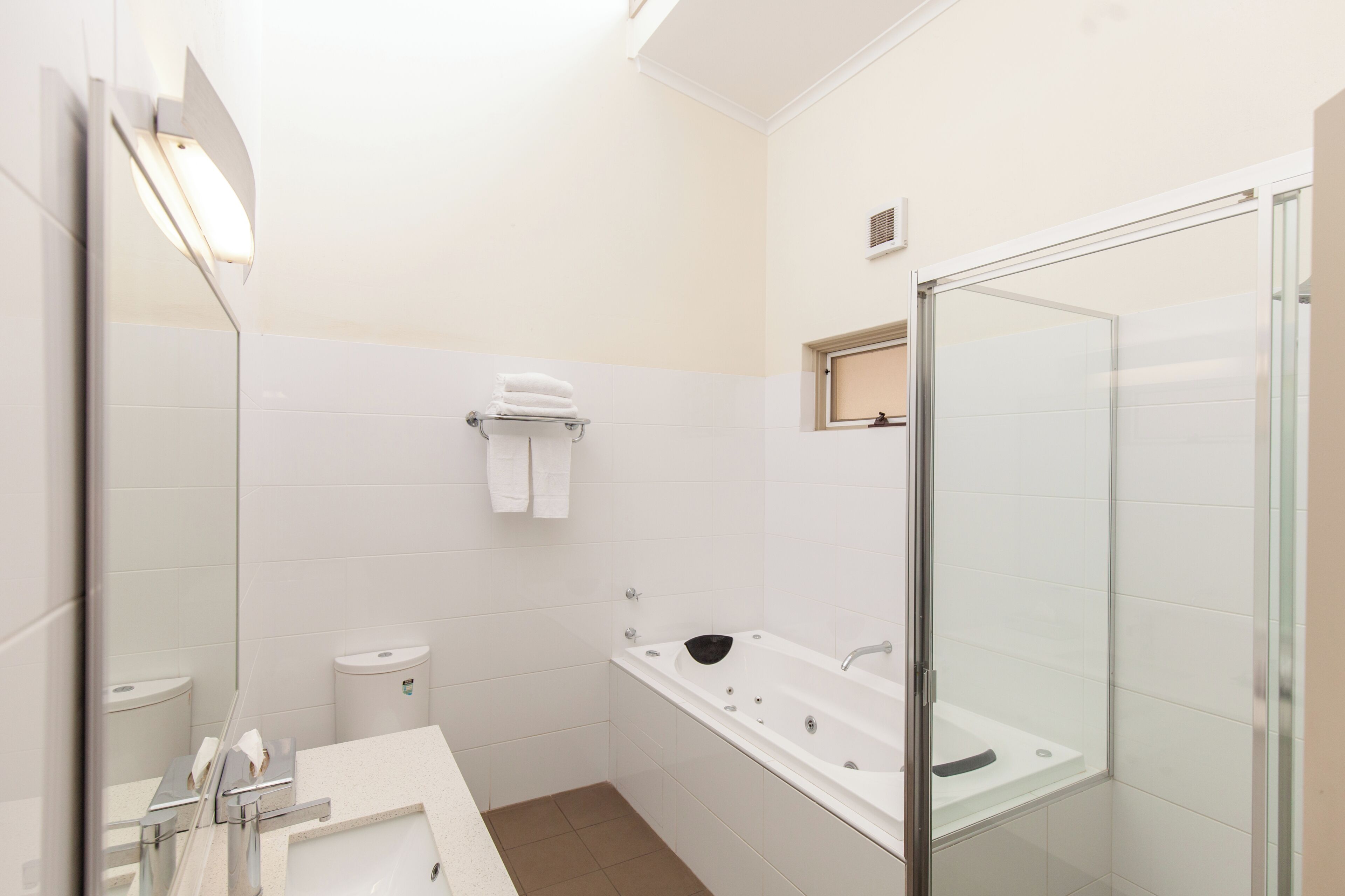 A modern bathroom with a glass shower enclosure, a white sink, and a mirror.