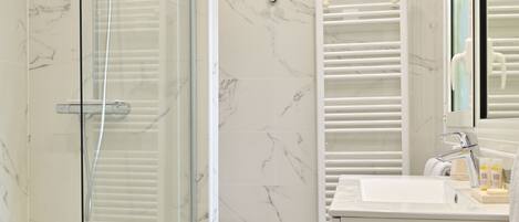 Un bagno moderno con doccia vetro, lavandino bianco e pavimento in marmo.
