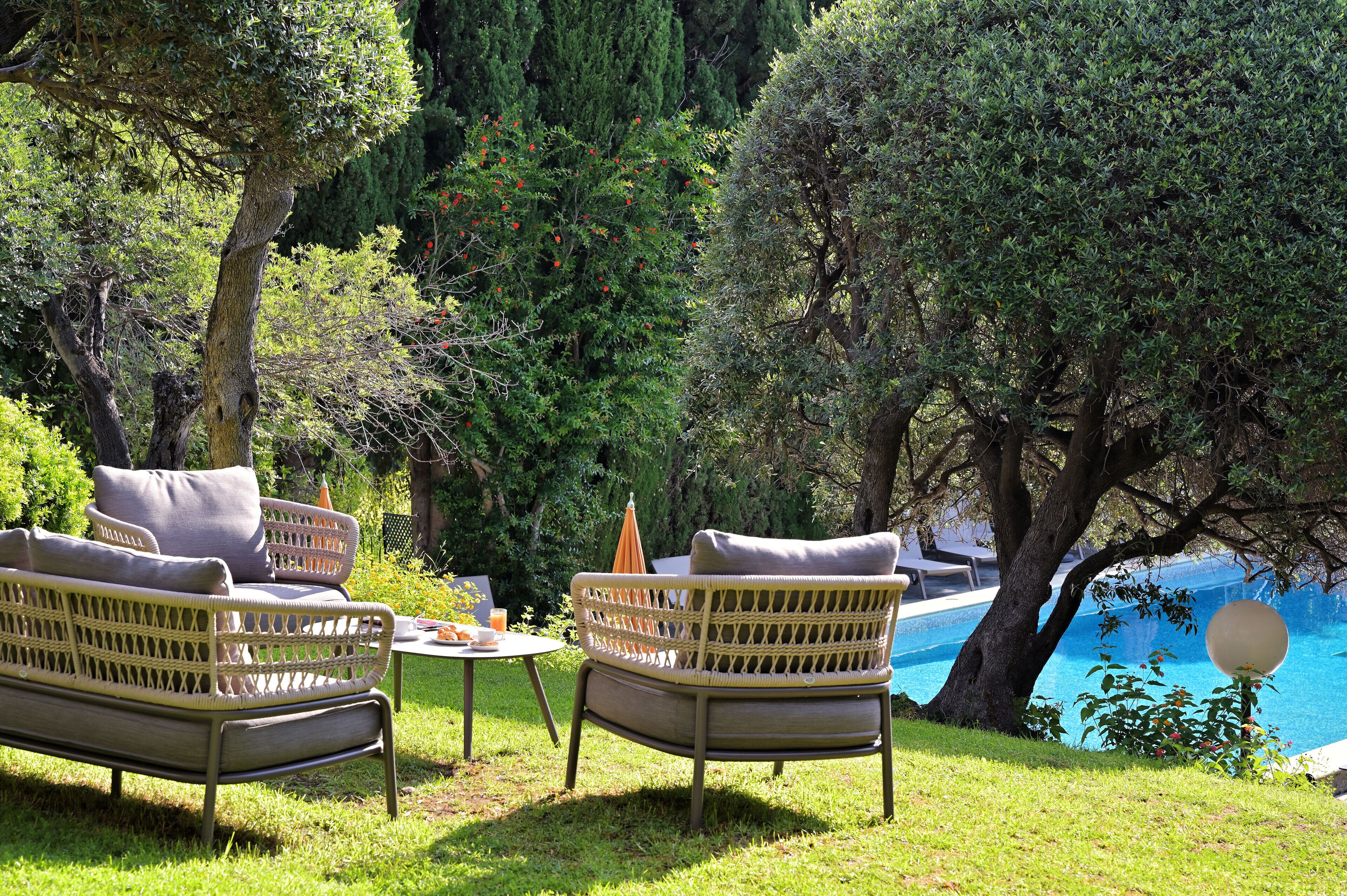 A garden with wicker furniture and a pool.