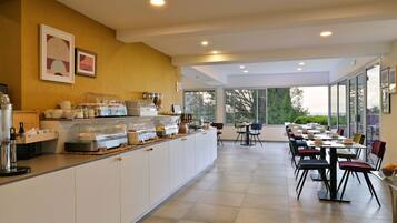 A modern cafe with a long counter, various coffee machines, and a seating area with tables and chairs.