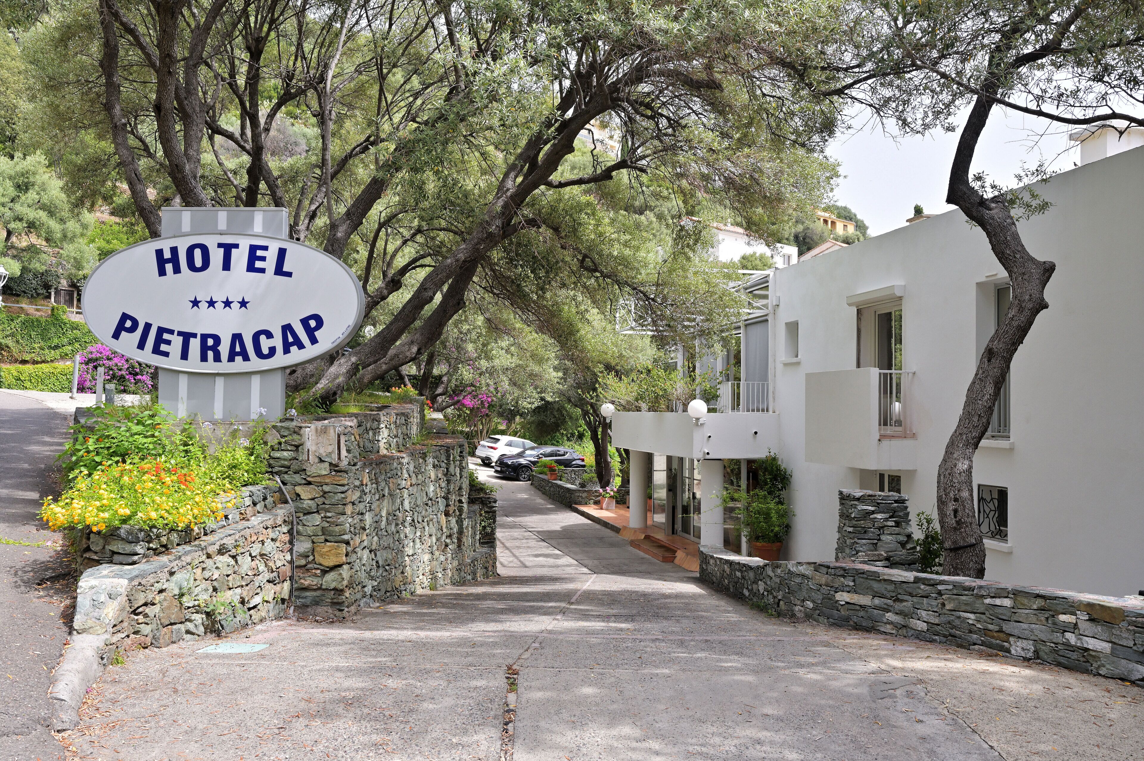 A sign for Hotel Pietracap, surrounded by stone walls and greenery.