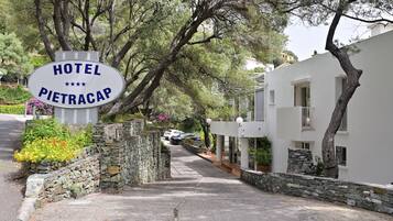 Une enseigne indiquant l’hôtel Pietracap, entourée de murs de pierre et de verdure.
