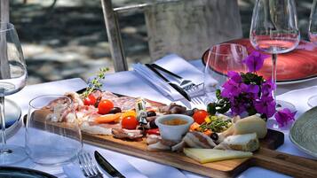A table set with a charcuterie board, wine glasses, and a vase of purple flowers.