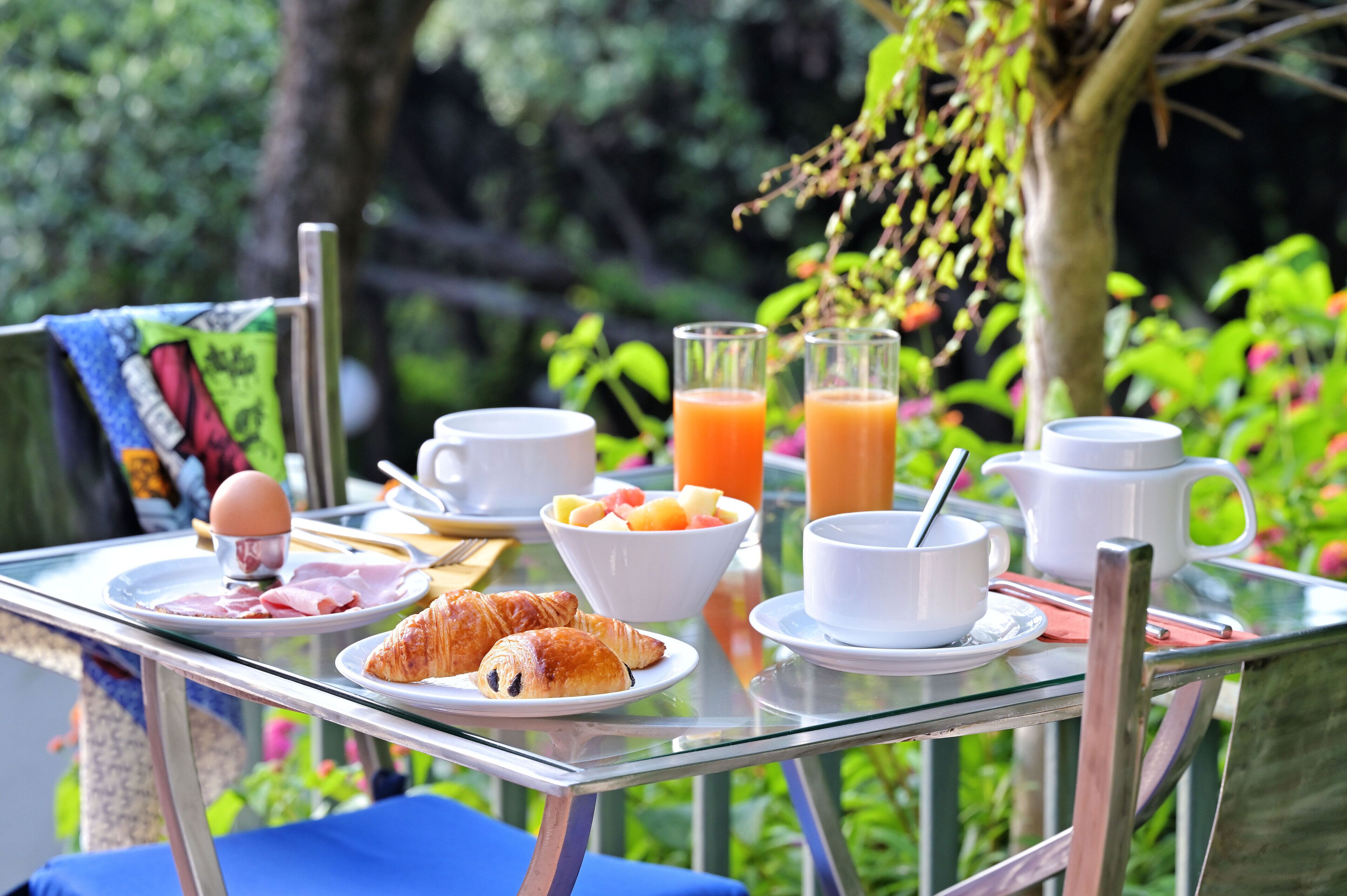 Uma mesa de café da manhã com croissants, ovos, frutas e suco.