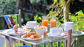 Uma mesa de café da manhã com croissants, ovos, frutas e suco.