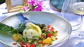 Un plato de comida con salsa blanca, verduras y una copa de vino blanco.