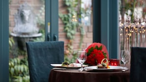 A table set for a meal with a red flower centerpiece, a glass of water, and a plate of food. - Hotel Monterey La Soeur Ginza (Tokyo)
