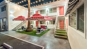 A covered outdoor area with a staircase, red umbrellas, and a small seating area. - Santa Monica Hotel (Santa Monica)