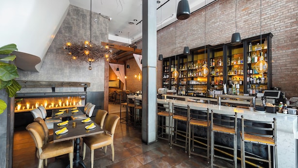 A modern bar area with a brick wall, hanging lights, and a bar counter with stools. - The O Hotel, Trademark Collection by Wyndham (Los Angeles)