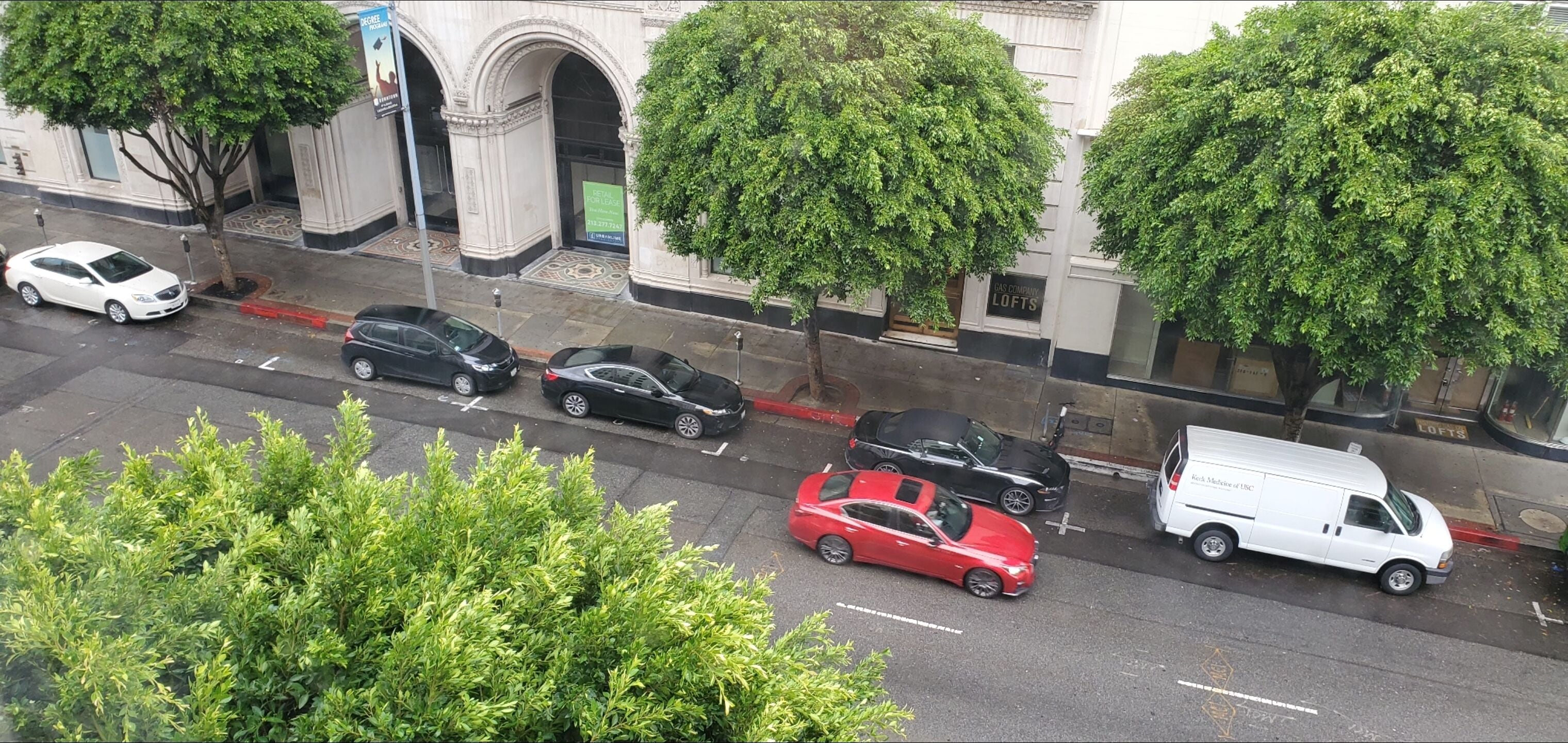 A street view with parked cars and a building with a sign that reads "LOFTS".