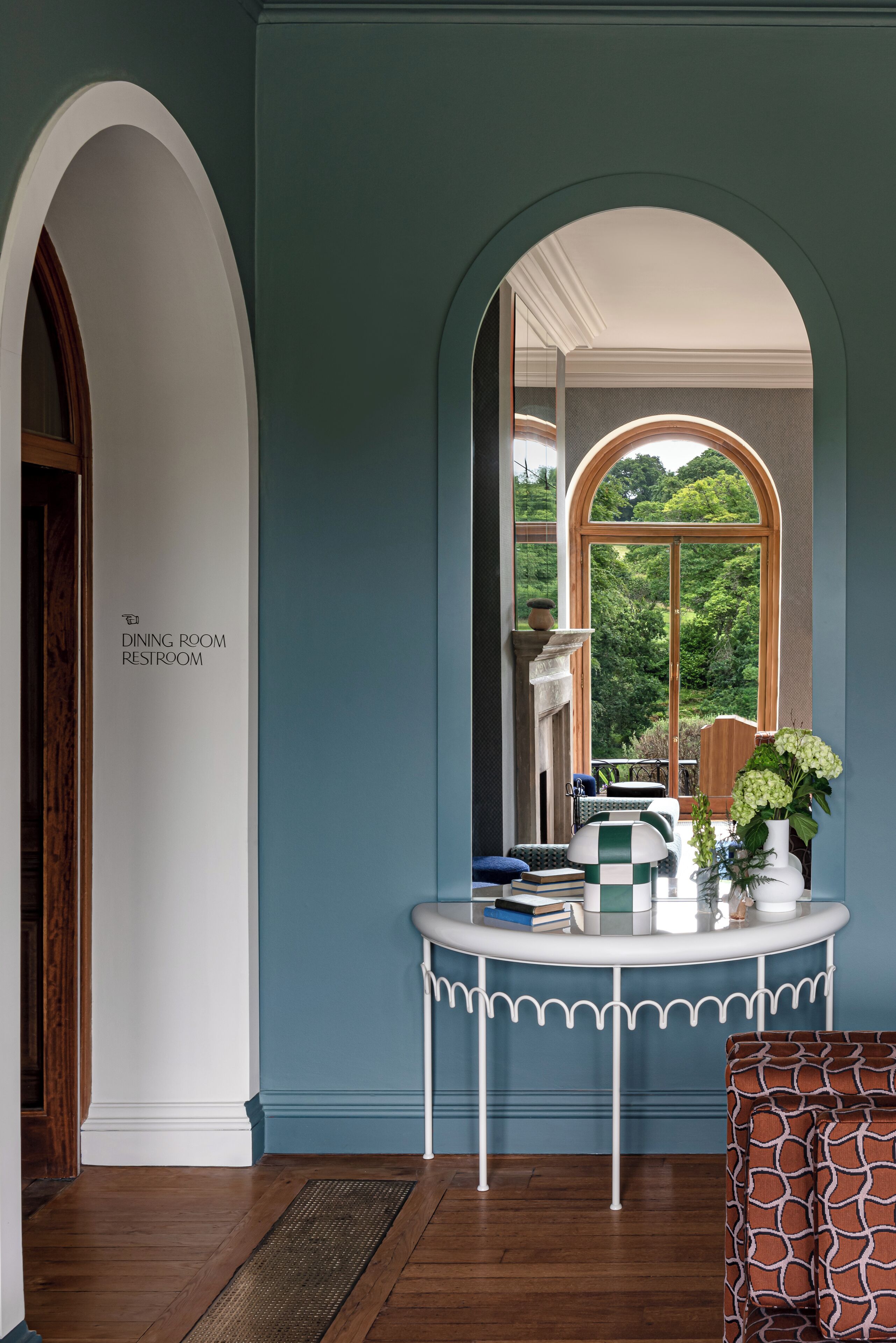 A dining room with a view of the outdoors, a table with books and a vase, and a sign indicating the room's purpose.