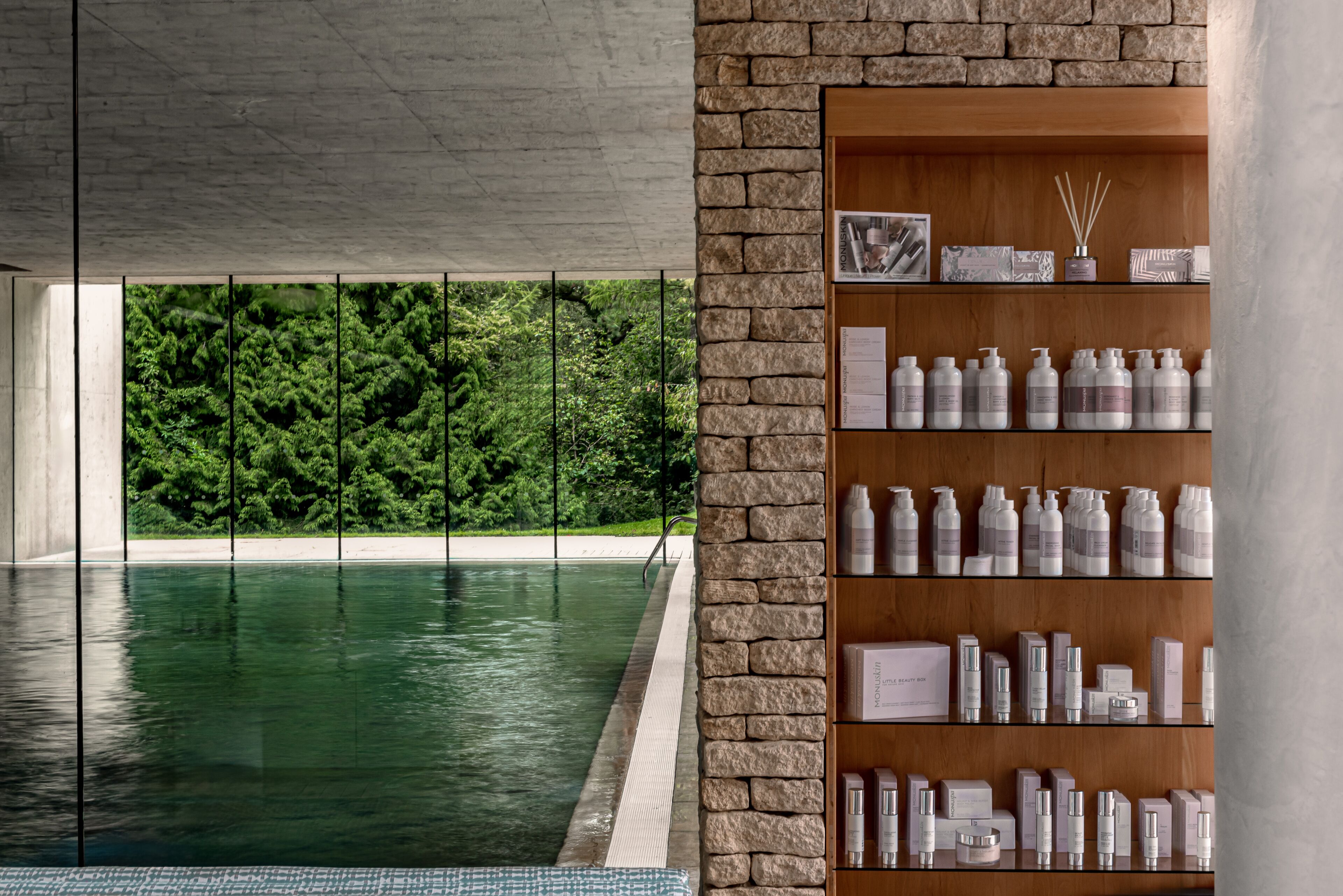 A modern indoor pool area with a clear view of lush greenery outside.