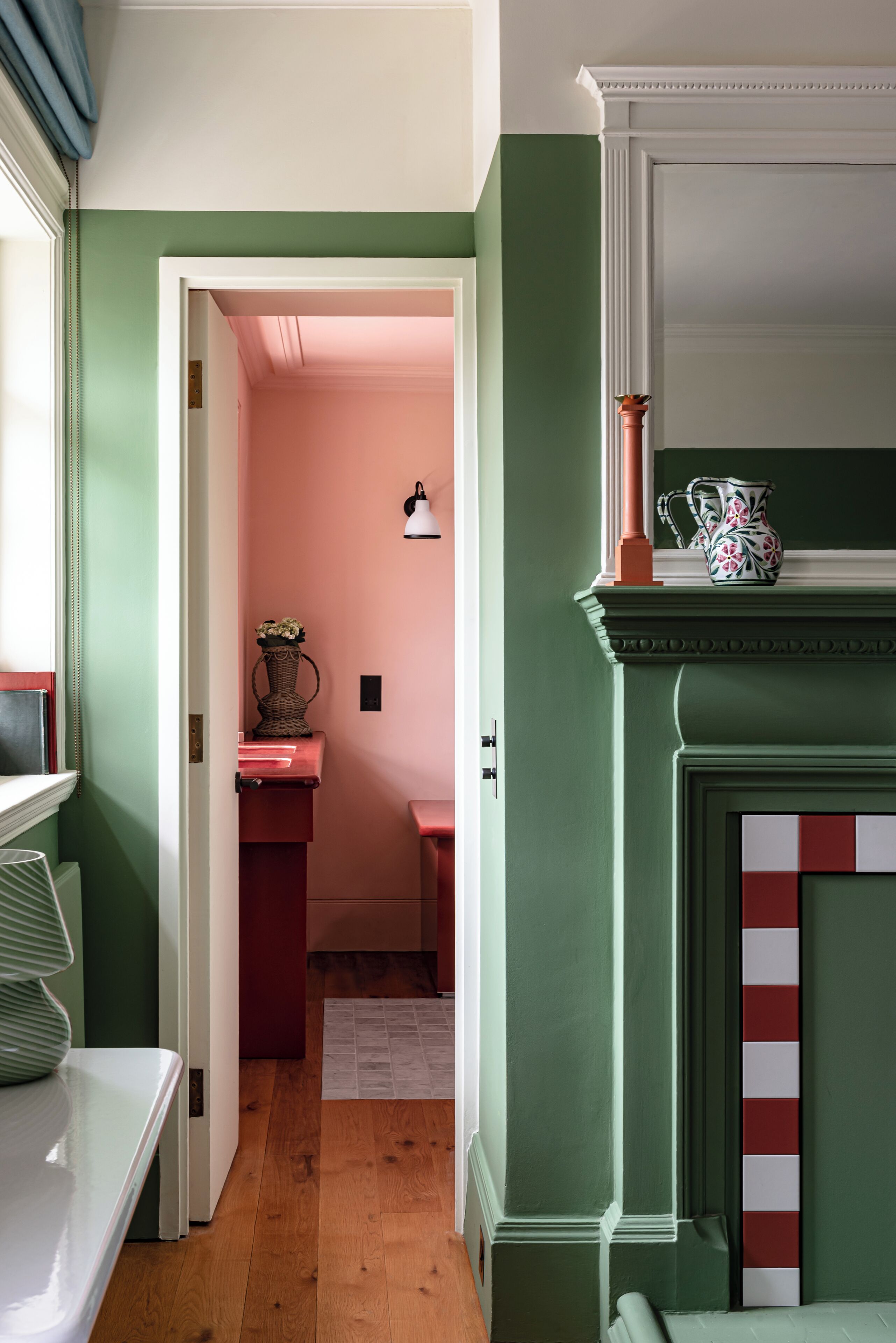 A hallway with a green wall, a white door, and a pink room in the background.