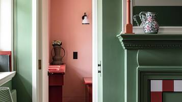 A hallway with a green wall, a white door, and a pink room in the background.