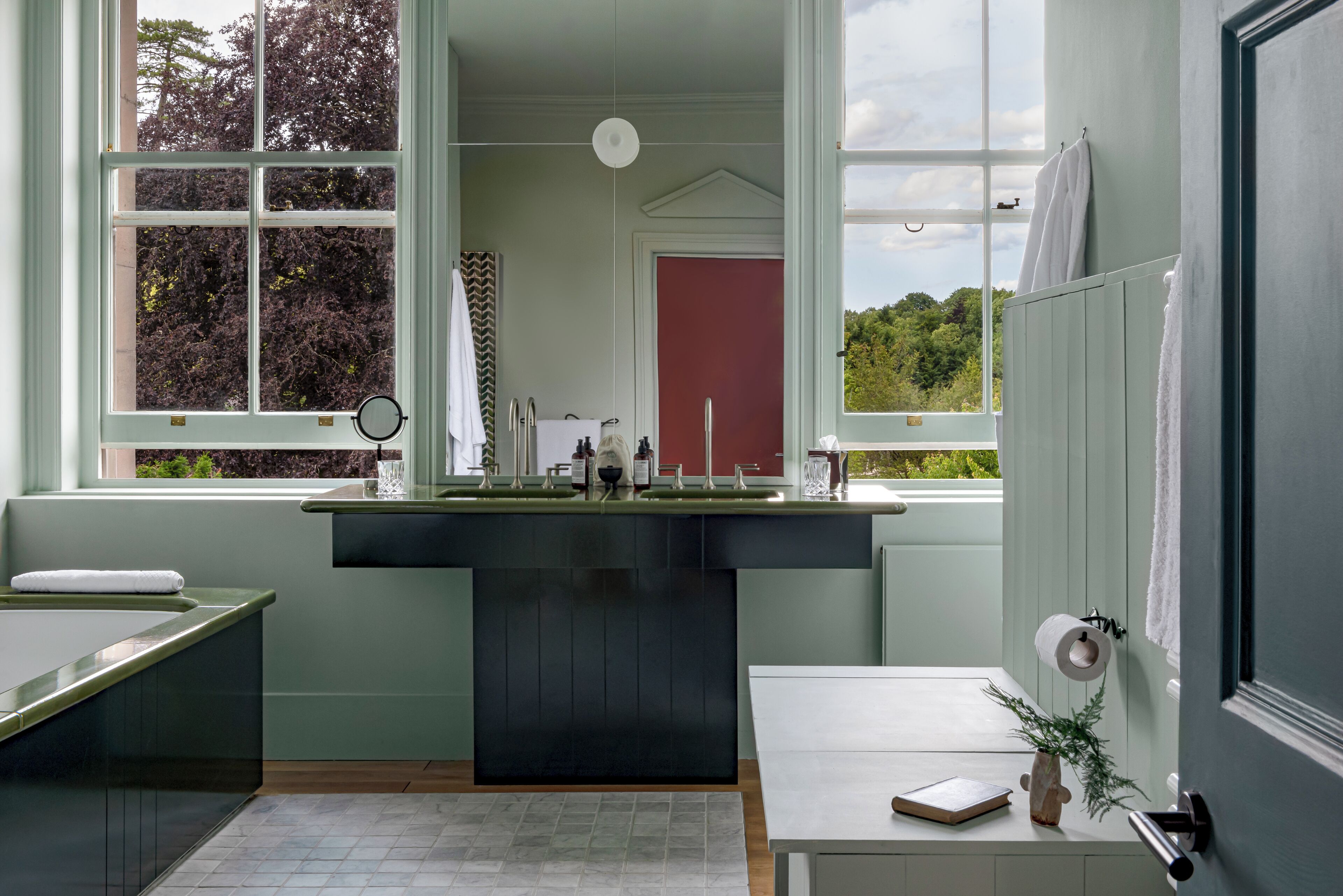 A modern bathroom with a large window, a sink, and a mirror.