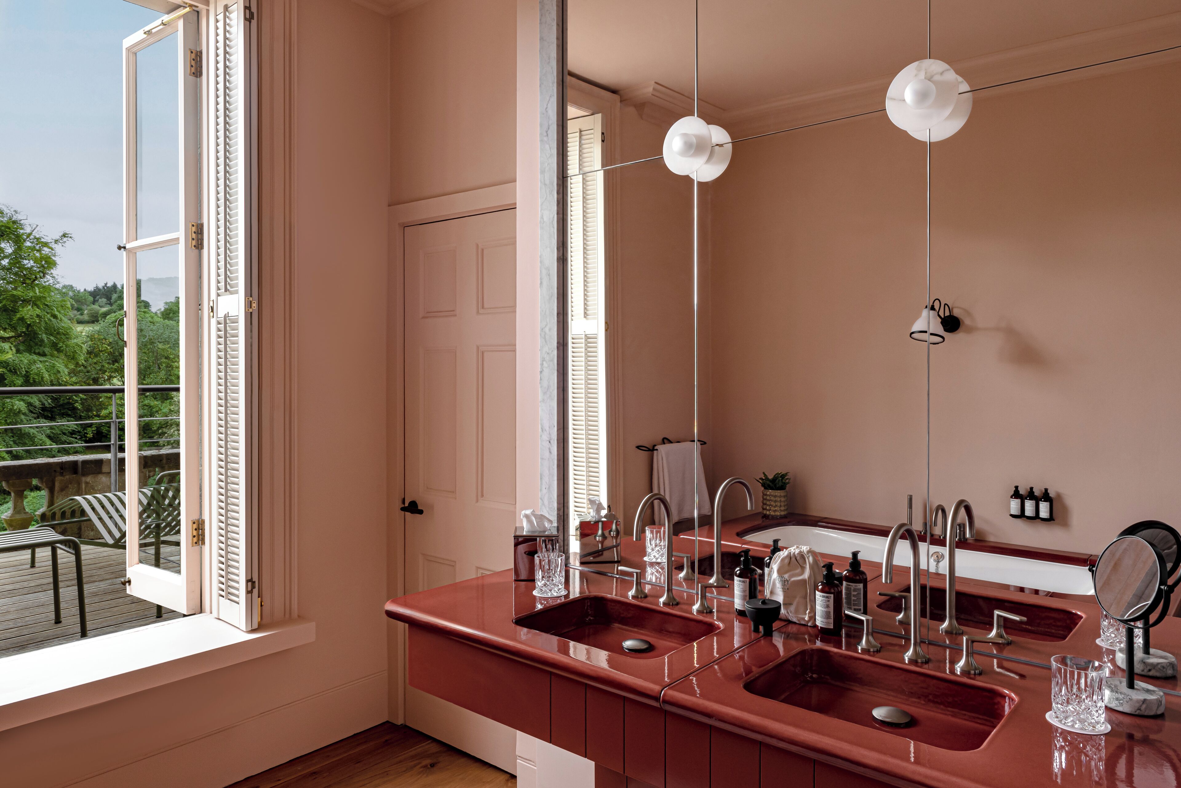 A modern bathroom with two sinks, a large mirror, and a ceiling light fixture.