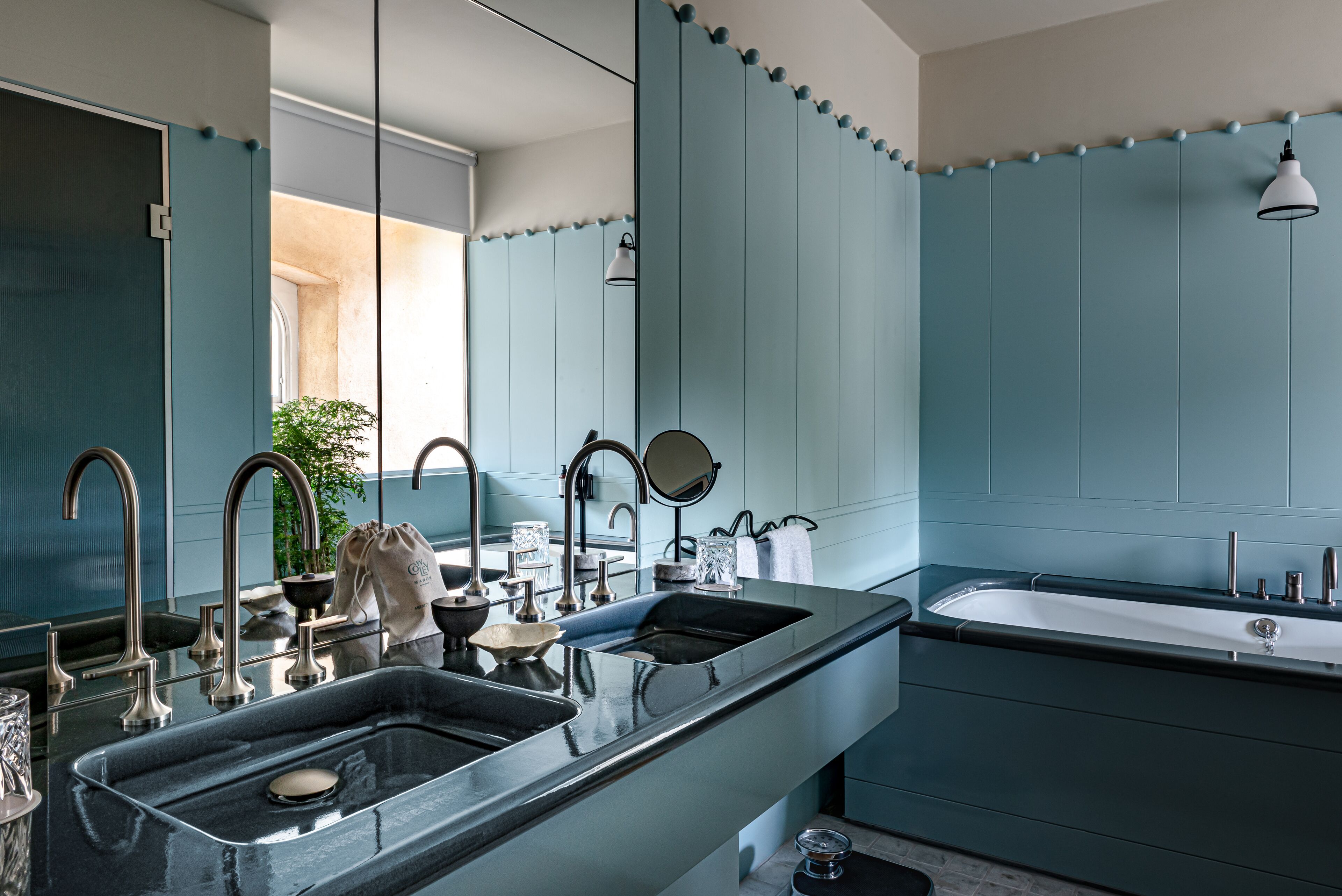 A modern bathroom with a large mirror, two sinks, and a bathtub.