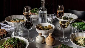 A dining table set with various dishes, glasses of wine, and a bottle of water. - Cowley Manor Experimental (Cheltenham)