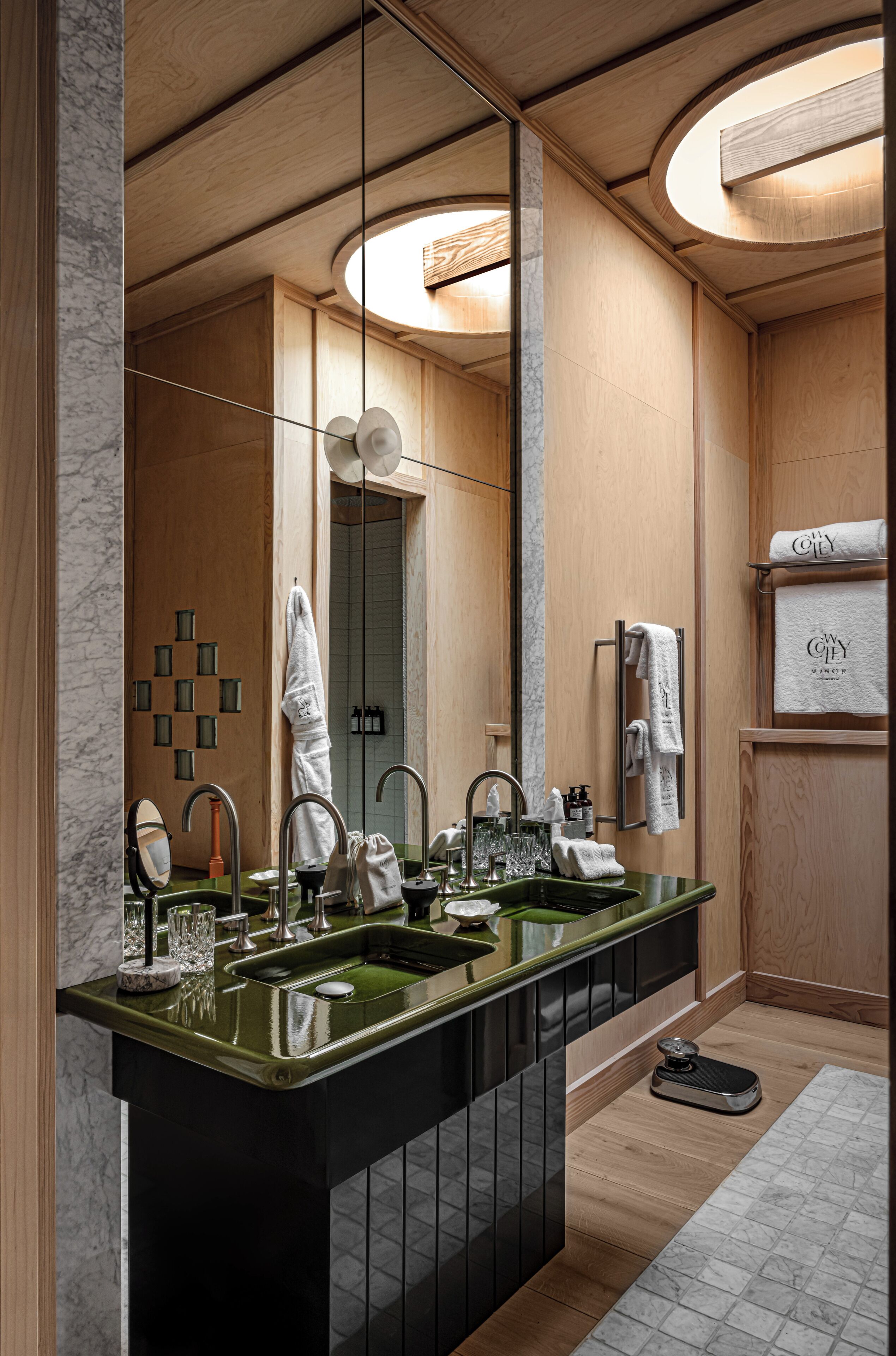 Un baño moderno con un espejo grande, dos lavamanos y paneles de madera.