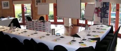 A conference room with tables set for a meeting, whiteboards, and a banner with logos.