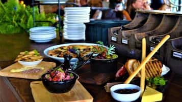 A buffet setup with various dishes, including a salad, cheese, and bread, on wooden boards.
