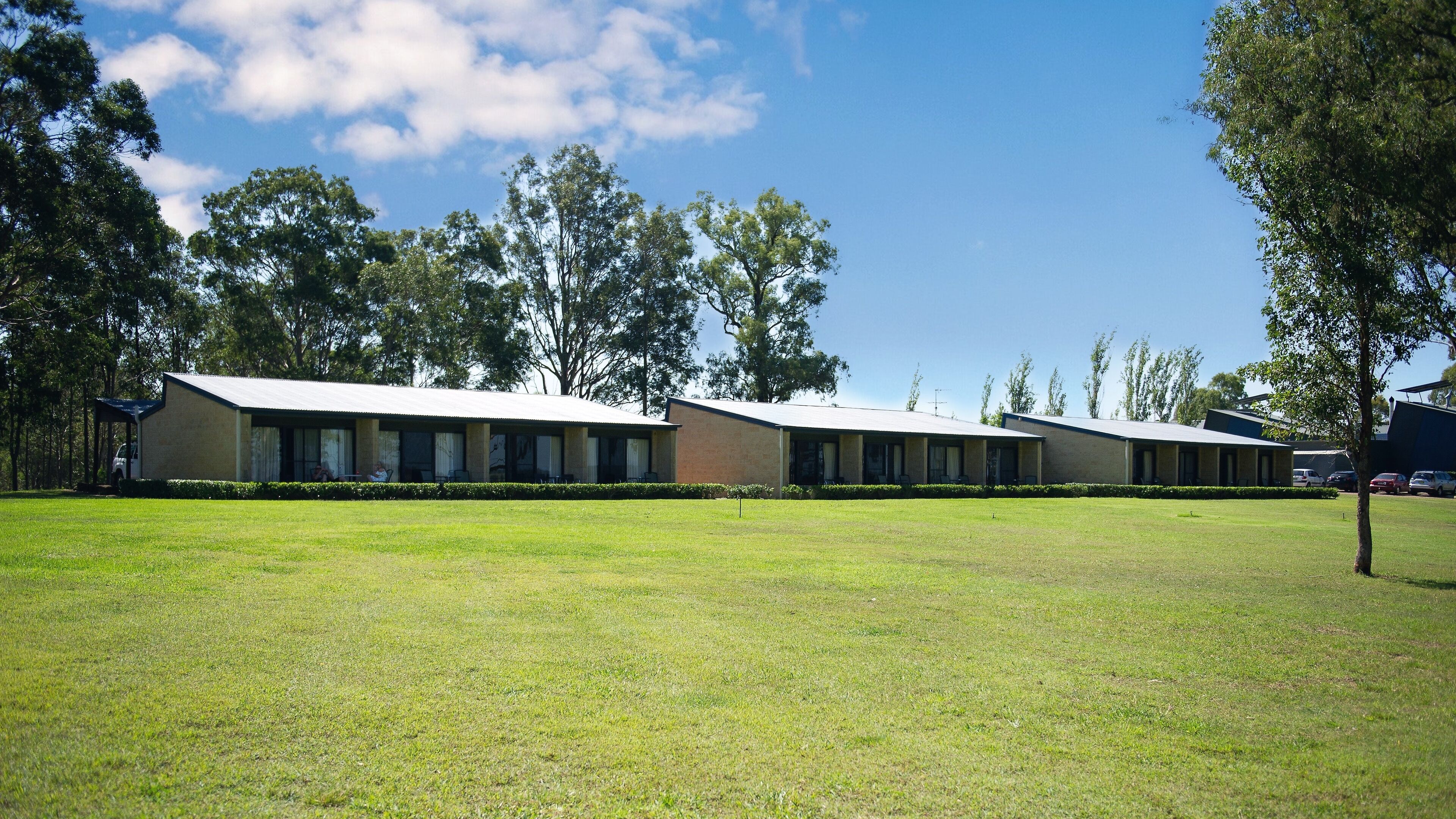 A row of motel-style buildings with a flat roof and a covered outdoor area.