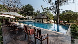Um deck de madeira com espreguiçadeiras e piscina.