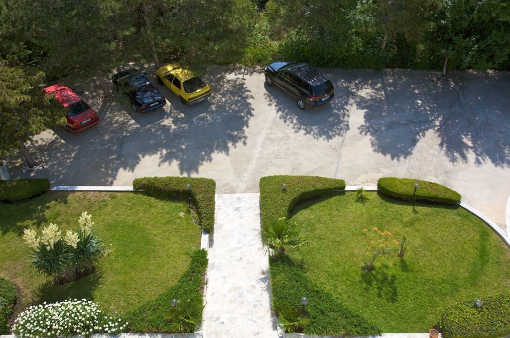 Eine Luftaufnahme eines Parkplatzes mit fünf Autos und gepflegten Rasenflächen mit geschnittenen Hecken.