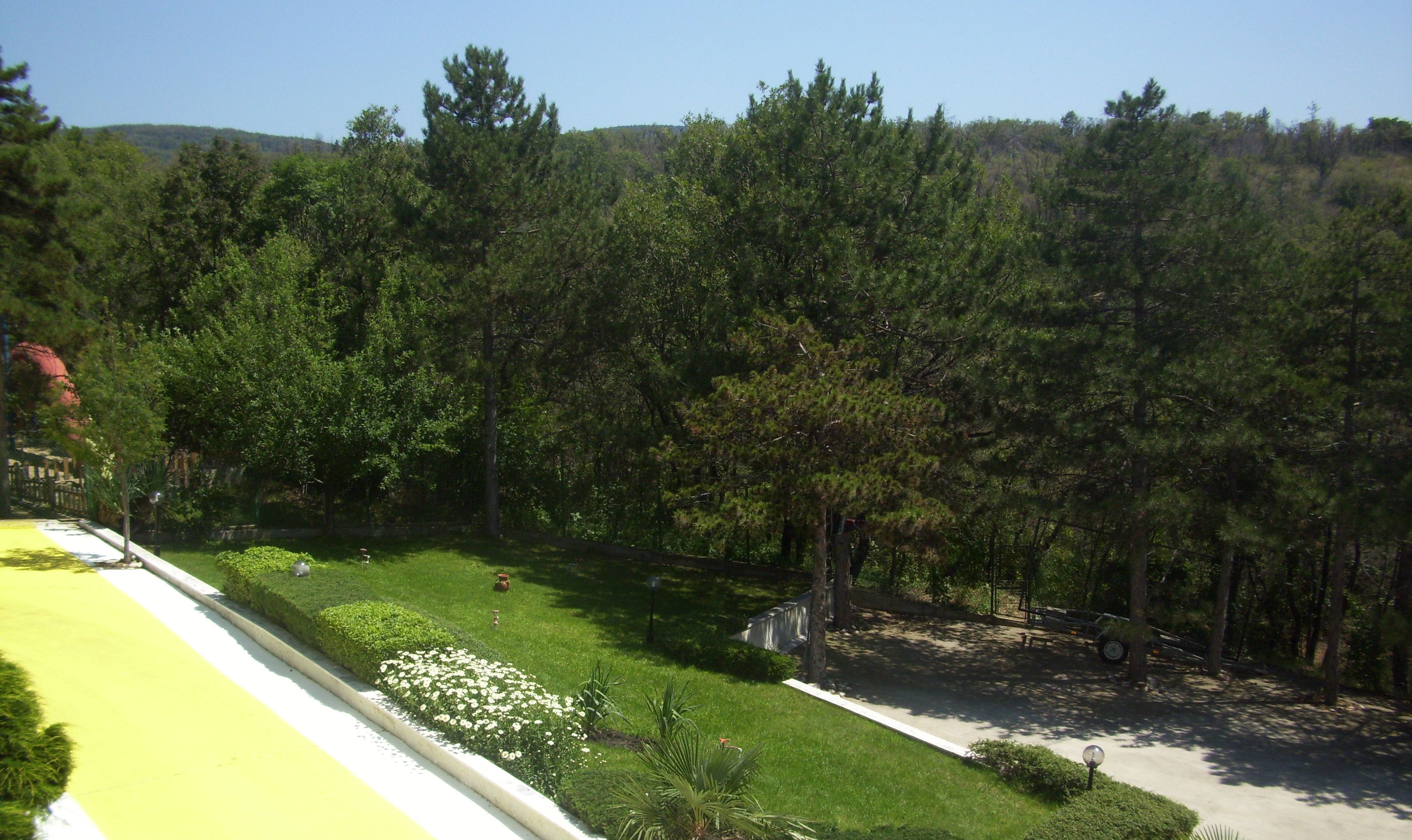 A landscaped area with a lawn, flower beds, and a paved path.