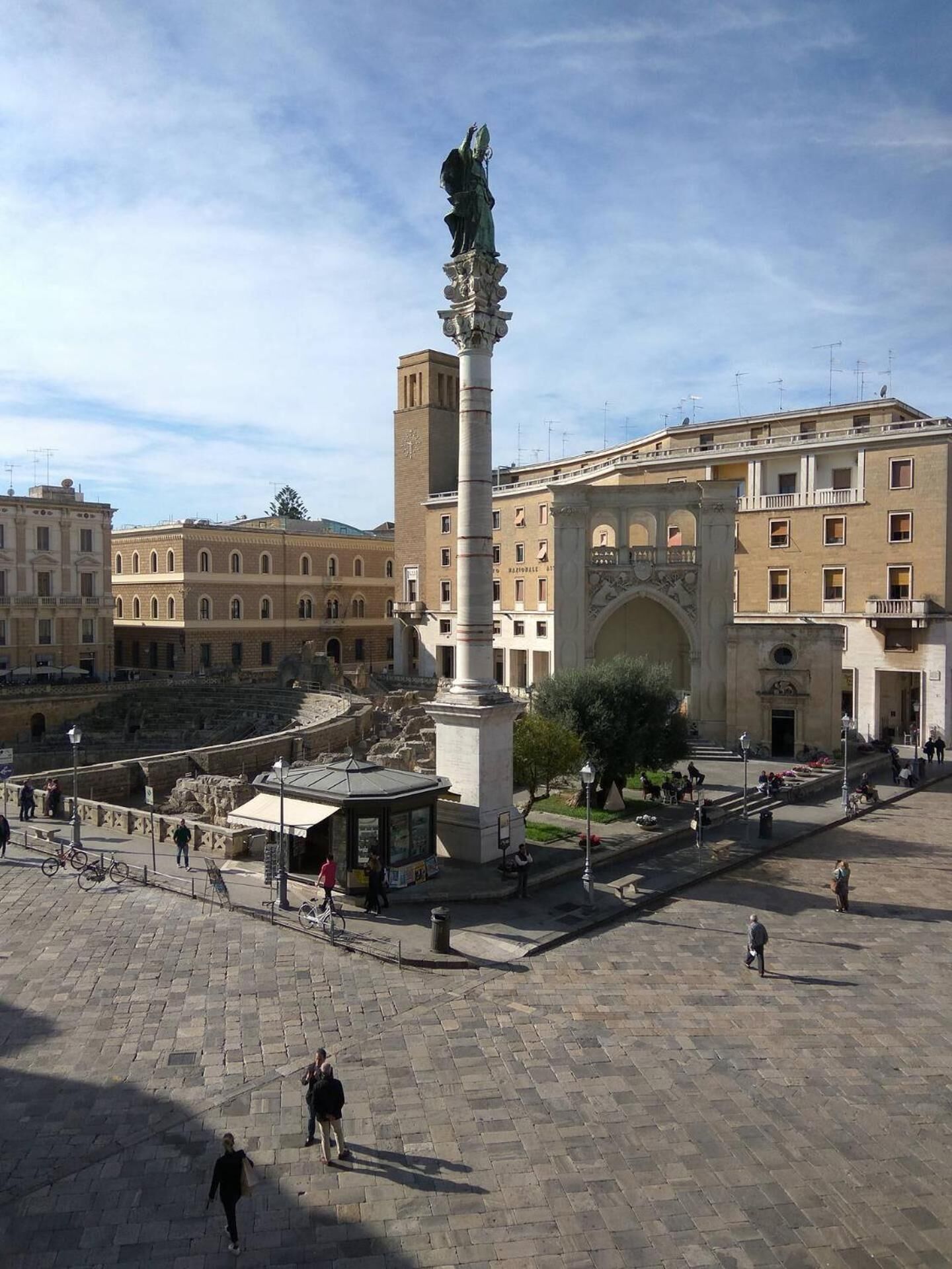 Una plaza con un monumento central, edificios circundantes y cielo despejado.