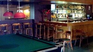 A bar area with wooden walls, a pool table, and multiple bar stools. - Sadie Thompson Inn (Pago Pago)