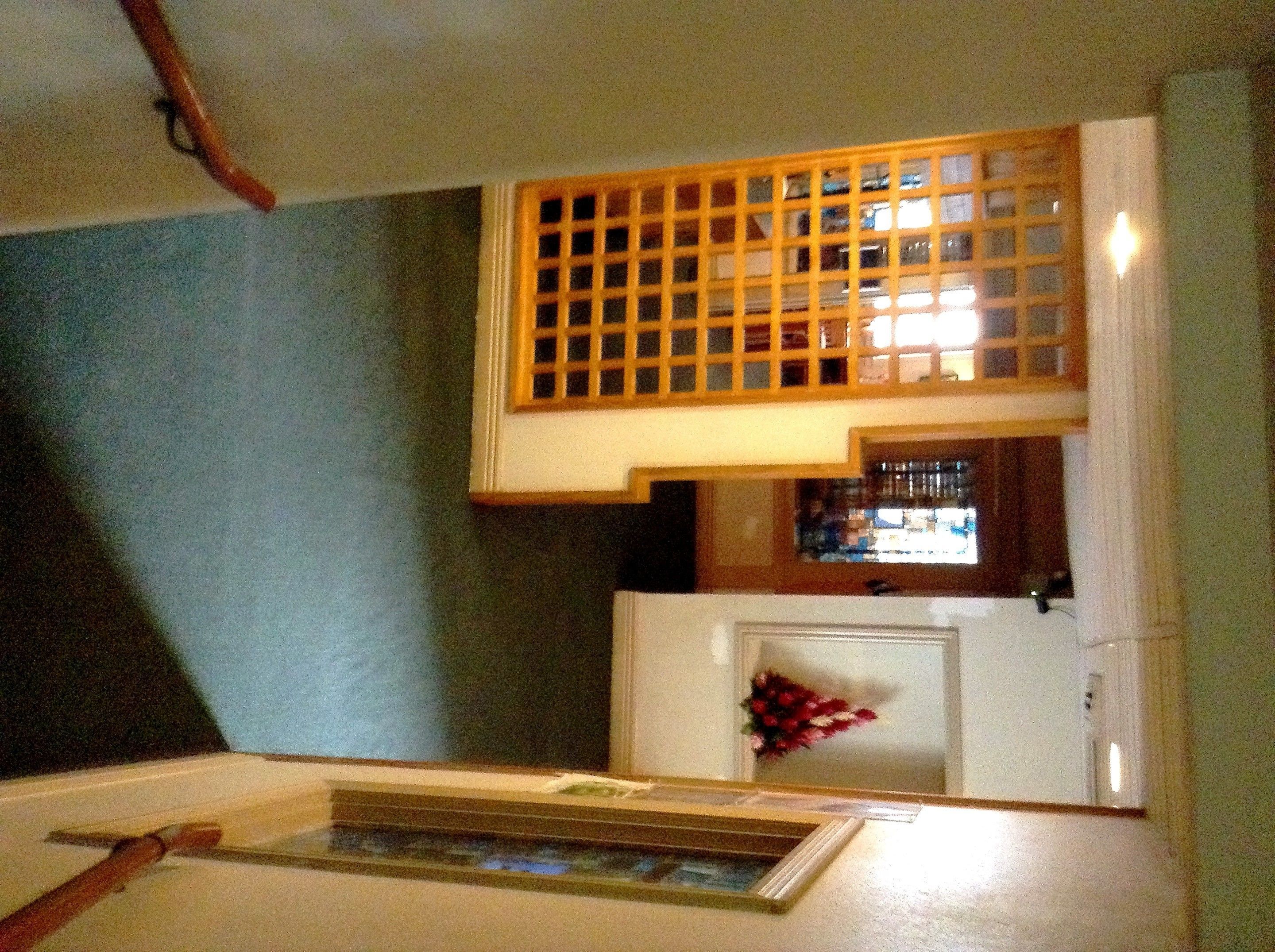 A room with a wooden ceiling, a white fireplace with a flower arrangement, and a window with a grid pattern.