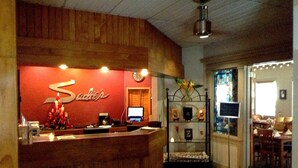 A reception area with a wooden counter, a clock, and a wall-mounted sign. - Sadie Thompson Inn (Pago Pago)