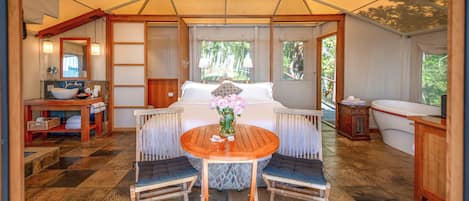 A tented accommodation with a dining area, a bed, and a bathroom.