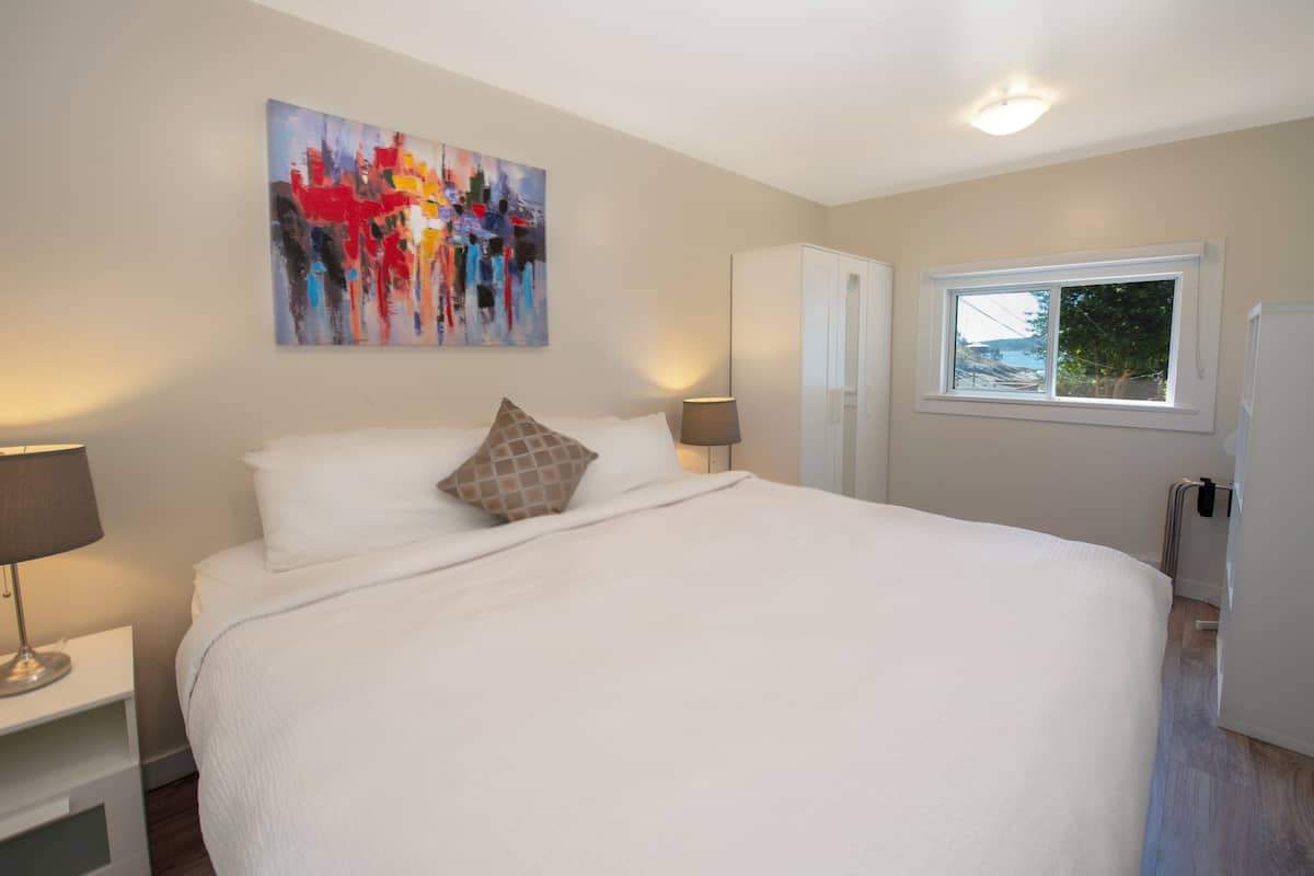 Quarto com uma cama grande, um quadro na parede, uma janela e um guarda-roupa.