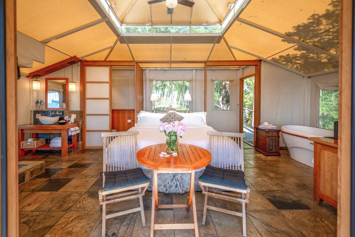 Acomodação em tenda com área de refeições, cama e banheiro.