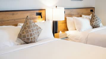 A hotel room with two beds, a bedside lamp, and a wooden headboard.