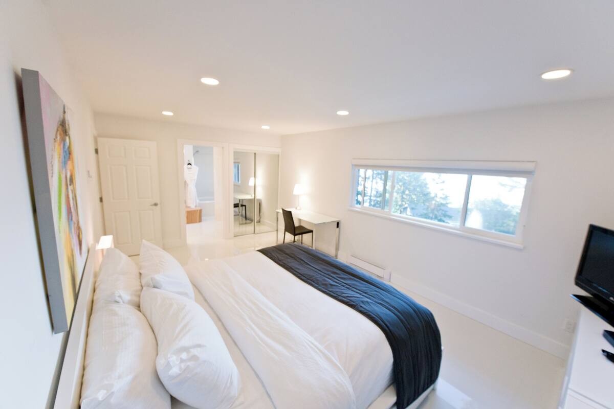 Um quarto moderno com uma cama grande, uma escrivaninha e uma televisão.