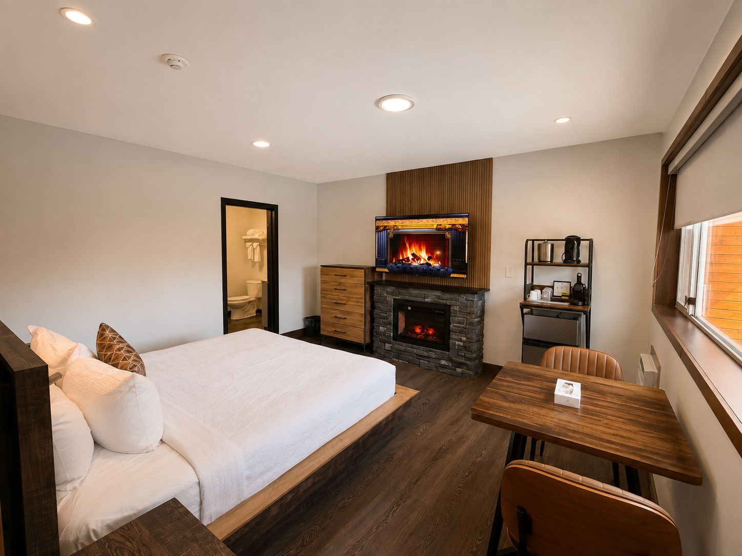 Une chambre d’hôtel moderne équipée d’un lit, d’une cheminée, d’une table à manger et d’un petit coin cuisine.