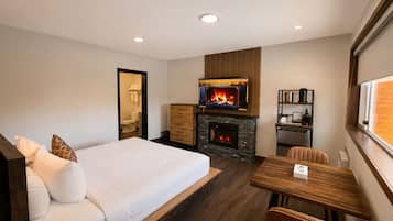 Une chambre d’hôtel moderne équipée d’un lit, d’une cheminée, d’une table à manger et d’un petit coin cuisine.