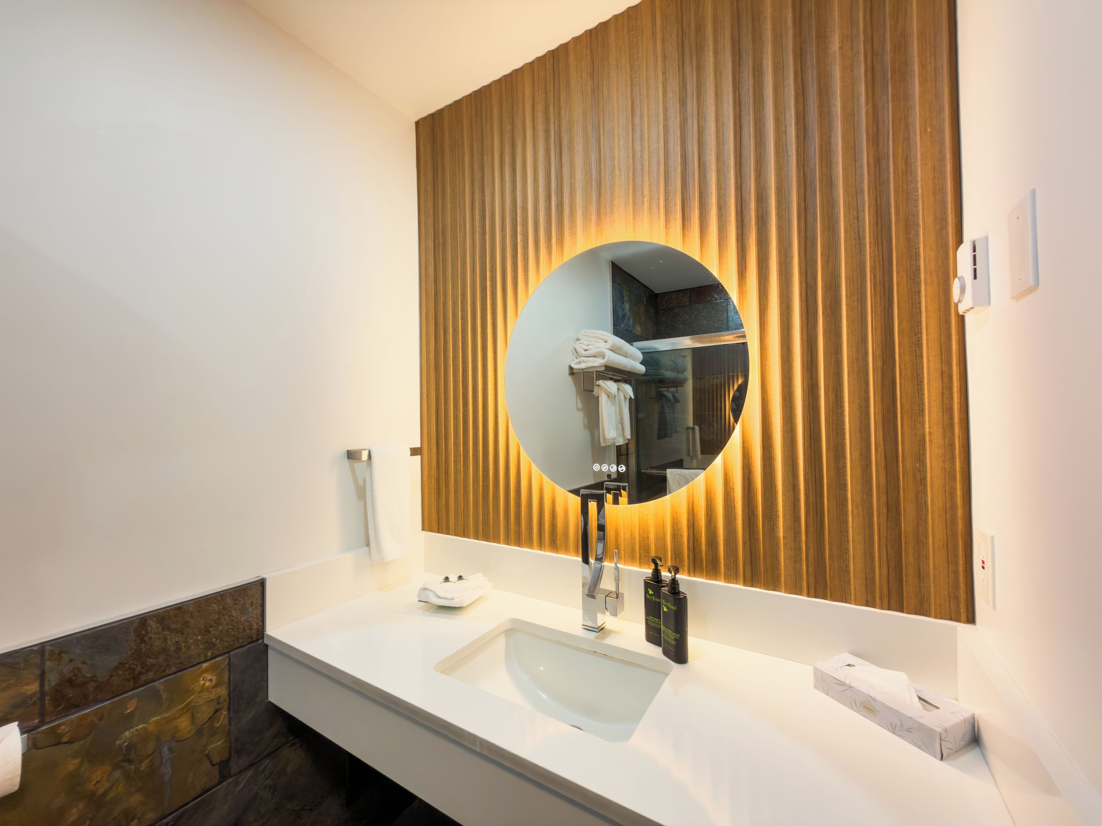 A modern bathroom with a large mirror, a sink, and a towel rack.