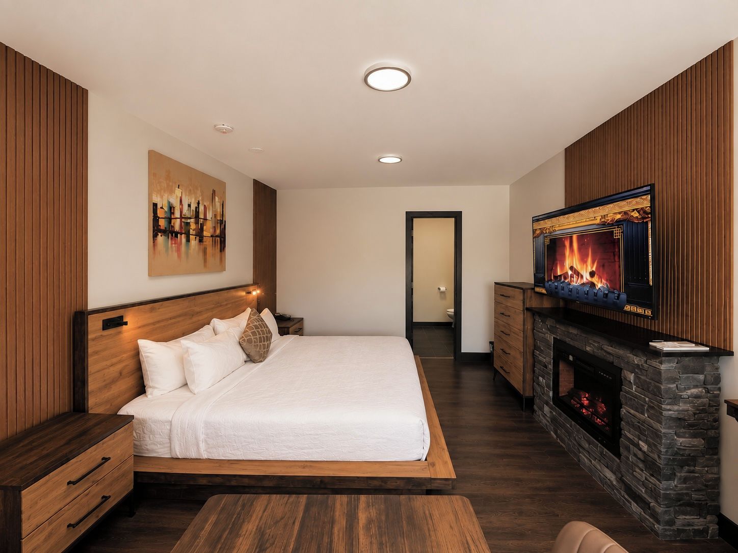 Un dormitorio moderno con una cama grande, un televisor y una chimenea.