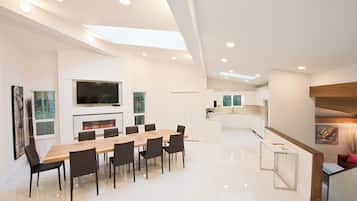 A spacious, modern kitchen with white cabinetry, a central island, and a dining area with a long wooden table and chairs.