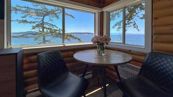 A wooden cabin room with two black chairs, a round table, and a vase of flowers.