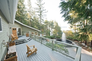 A wooden deck with outdoor seating, a fire pit, and a view of a forested area. - Rockwater Secret Cove Resort (Halfmoon Bay)