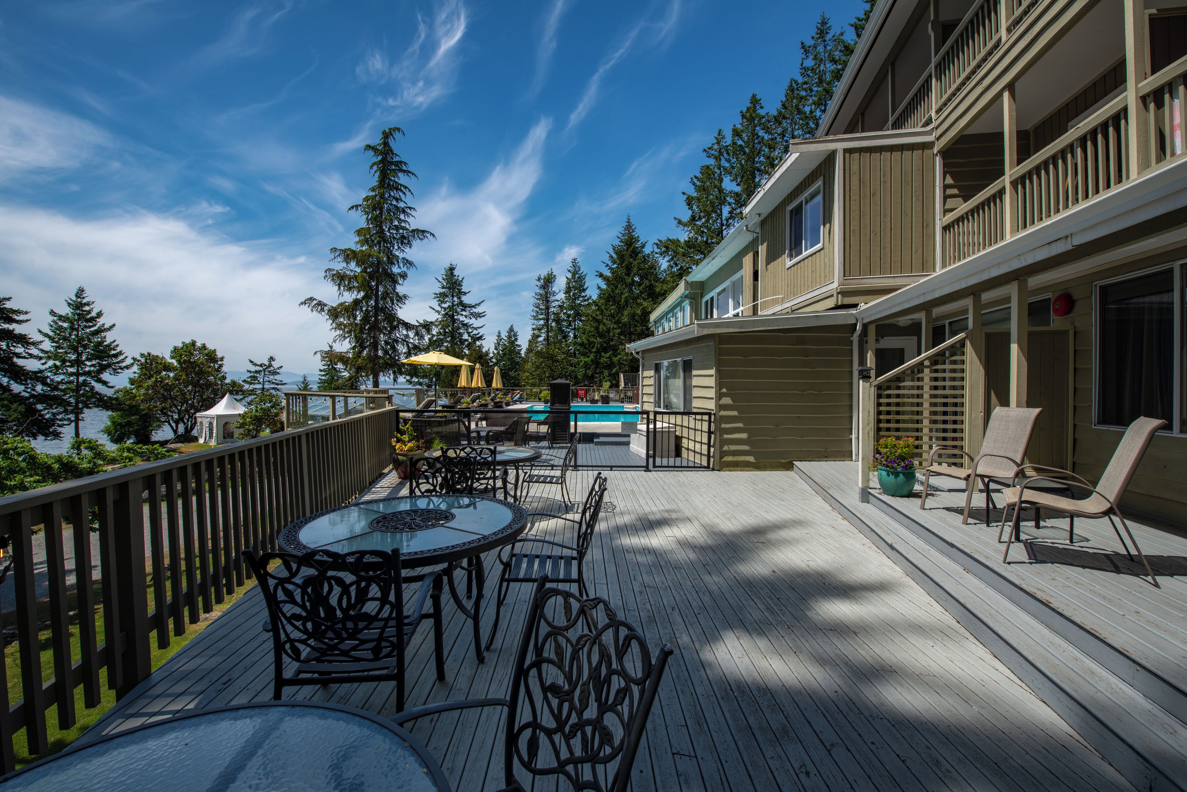 Une terrasse avec des sièges extérieurs, une piscine et un bâtiment doté de plusieurs balcons.