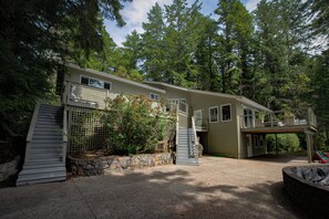 Une maison à deux étages dotée d’un patio couvert, d’un mur de soutènement en pierre et d’une petite piscine.