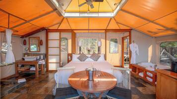 Alojamiento con tienda de campaña, cama, mesa con sillas, lavabo y ventana.